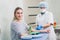 Preparation for blood test with beautiful young blond woman by female doctor in white coat medical uniform on the table