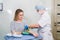 Preparation for blood test with beautiful young blond woman by female doctor in white coat medical uniform on the table