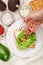 Preparation of bread toast with avocado, cottage cheese ricotta, coarse sea salt and pink pepper