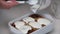 Preparation of cinnabons. A woman glazes baked cinnabons. The camera moves on a slider. Close-up