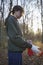 Preparation for the collection of garbage and plastic waste in the autumn forest. Young woman volunteer puts on gloves