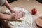Preparation cookies with cinnamon, cottage cheese and apples on kraft paper. Female hands rolling dough in meals