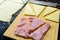 Preparation of croissants, stuffed with ham and cheese and painted with egg yolk, on a wooden board, ready to bake