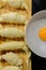 Preparation of croissants, stuffed with ham and cheese and painted with egg yolk, on a wooden board, ready to bake