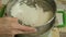 Preparation of dough for baking, the woman sift the flour through a sieve.