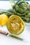 Preparation of heads of fresh raw artichokes plants from artichoke plantation in Argolida, Greece ready to cook with lemon