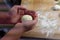 Preparation of homemade fruit dumplings with plums. Czech specialty of sweet good food. Dough on kitchen wooden table with hands