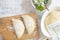 Preparation of homemade pies with cheese and fresh herbs filling. On a wooden board, dough and rolling pin, a towel with a pattern