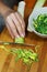 Preparation of a leek salad, a woman`s hand, a knife, a bowl