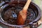 Preparation of red mole, a typical Mexican dish in a clay pot with a giant wooden spoon over the fire of a stove with all the inte