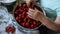 Preparation of strawberry jam. Hands of an elderly woman clean peel large juicy strawberries from leaves and stalks