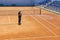 Preparation of a tennis court watering from a hose. A man watering a tennis court