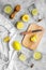 Prepare refreshing beverage lemonade. Lemons, juicer, bottle, knife, cutting board on grey stone background top view