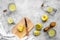 Prepare refreshing beverage lemonade. Lemons, juicer, bottle, knife, cutting board on grey stone background top view