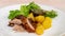 Prepare to serve delicious roasted pork with roasted potato and green vegetables in a white dish.