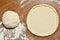 Prepared dough for pizza in the form of a circle on the table in the kitchen