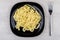 Prepared pasta in black plate on wooden table