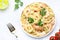 Prepared pasta with shrimp on plate with tomatoes and parsley, white table background. Top view