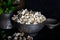 Prepared popcorn in frying pan, corn seeds in bowl and corncobs on dark background