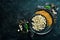 Prepared popcorn in frying pan, corn seeds in bowl and corncobs on kitchen table.