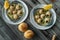 Prepared snails with butter sauce, white bread and spice on white salty plate on wooden background. Snails baked with