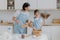 Preparing delicious meal and cooking together concept. Pleased mother looks attentively at how child whisks ingredients in bowl,