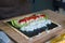 Preparing homemade sushi with white rice, tuna, tomatoes and salad on a dried nori seaweed sheet on bamboo mat