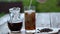 Preparing iced coffee. Milk is poured into glass with ice, outdoors.