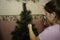 Preparing for the new year. Teen girl washes an artificial Christmas tree in the bathroom. Christmas tree in the shower