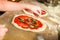 Preparing Pizza. Cook adds grated parmesan