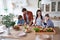 Preparing a salad. Young beautiful family cooking together in the modern kitchen at home. Mother and father teaching two