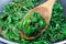 Preparing a side dish to steak, Wilted arugula or rocket salad in frying pan, horizontal, closeup