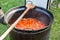 Preparing traditional Hungarian goulash soup bograch in a large metal pot cauldron