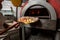 Preparing traditional italian pizza. chef holding shovel for pizza, bakes dough in a professional oven in interior of modern