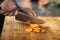 Preparing Vegan Meal -  Chef Cutting Carrot on Wooden Cutting Board