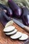 Preparing vegetable dish. Eggplant and eggplant slices on wooden cutting board and background, vertical