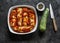 Preparing zucchini cannelloni with tomato sauce in a baking dish on a dark background, top view. Raw food ingredients