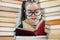 Preschool age girl in big glasses reading a red book behind arch made of books