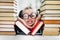 Preschool age girl with dimples in big funny glasses among a pile of books