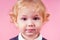 Preschool age little boy beauty king curls blonde hairstyle smiling toothy smile in the studio on a pink background