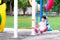 Preschool Asian children are riding in red swings and showing excited faces. The 2 year old boy plays swings on the playing field