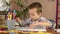 A preschool boy learns to write, draw with a pen in a notebook.He is preparing for lessons.