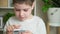 A preschool boy plays a game on a smartphone, runs his fingers across the screen and talks