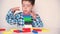 A preschool boy plays multi-colored wooden blocks, builds a tower