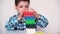 A preschool boy plays table jenga, carefully builds a tower of colorful wooden blocks. May 9, 2022, Zaporozhye, Ukraine