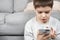 A preschool boy uses a smartphone, plays games on his phone, place for text