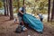 Preschool boys pitching a tent with their father in summer forest