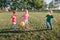 Preschool Caucasian girl boys friends playing soccer football on playground grass field outside. Happy authentic candid childhood