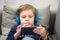 Preschool child listens to music on a smartphone while lying at home on the bed, boy plays on the phone