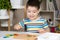 A preschool child plays with a mosaic, builds figures on a board, hammering nails with a hammer on multi-colored parts